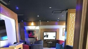 A modern lounge area with seating, a TV screen, and a bar area. - Ziyara for Serviced Apartments (Riyadh)