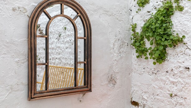 Una ventana con marco de madera, una pared blanca y hiedra verde trepando por la pared.