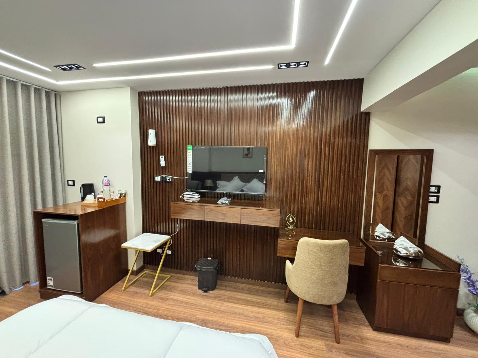 Una habitación de hotel con cama, escritorio, silla, televisor y minibar.