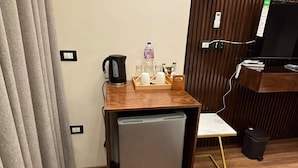 A compact room with a small refrigerator, a coffee maker, a water bottle, and a TV on a wooden stand. - Sheraton Star (Alexandria)