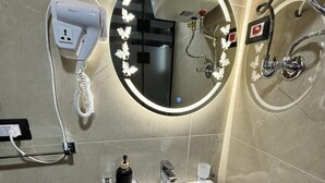 A bathroom with a white sink, a round mirror with lights, a hairdryer, and a towel rack. - Sheraton Star (Alexandria)