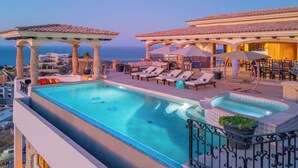 En pool på taket med solstolar, ett bubbelbad och en pergola.
