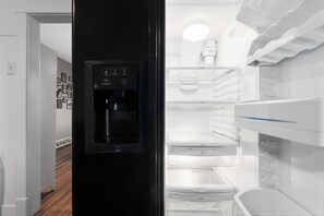 Eine moderne Küche mit integrierter Kaffeemaschine, einem Kühlschrank mit mehreren Fächern und einer Mikrowelle.