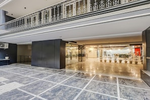 A modern hotel lobby with a marble floor, a reception desk, and a glass door entrance. - Deluxecloud Bay (Gurugram)