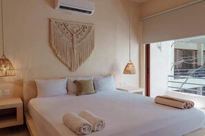Ein Hotelzimmer mit einem Bett, einer Wandweberei aus Makramee und Blick ins Freie.