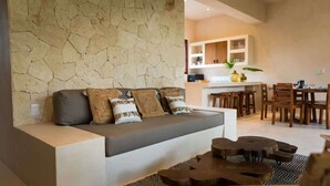 A modern living room with a sofa, a coffee table, and a kitchen area in the background. - Exclusive 3BR Sky Penthouse w/Private Rooftop Pool (Tulum)