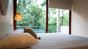 A bed with white bedding, a hanging light fixture, and a view of trees through a balcony. - Exclusive 3BR Sky Penthouse w/Private Rooftop Pool (Tulum)