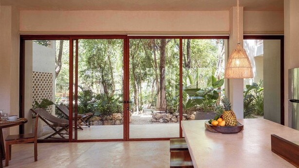 A modern kitchen with a large sliding glass door leading to a tropical garden. - Modern ground-level 3BR Retreat with Private Pool (Tulum)