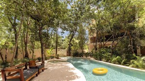 A pool area with wooden benches and a yellow inflatable ring. - Modern ground-level 3BR Retreat with Private Pool (Tulum)