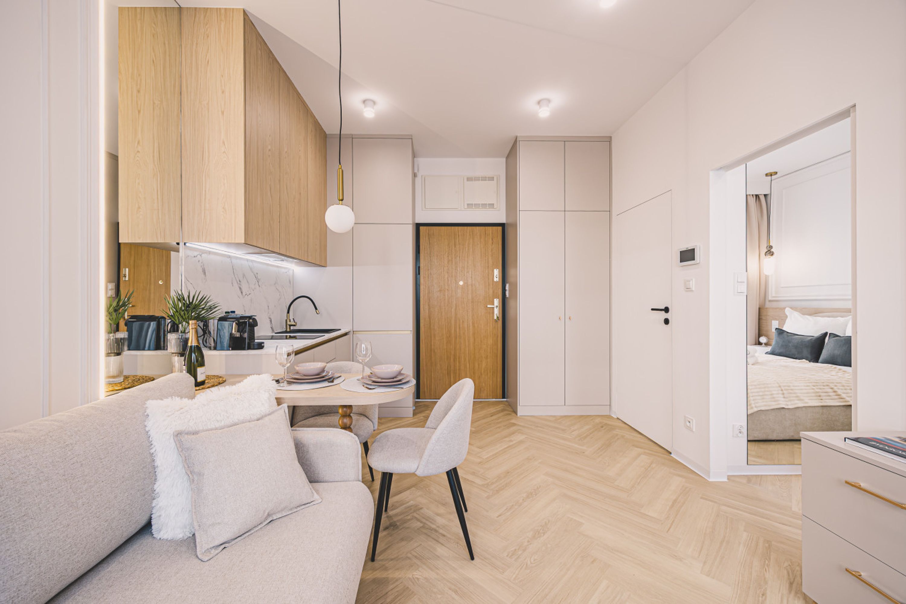 Una habitación moderna, bien iluminada, con sofá, mesa de comedor y kitchenette.