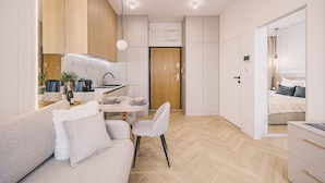 A modern, well-lit room with a sofa, dining table, and kitchenette. - Estilo Designerski Apartament z Tarasem (gmina Parzęczew)