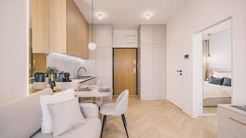 Una habitación moderna, bien iluminada, con sofá, mesa de comedor y kitchenette.