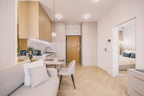 A modern, well-lit room with a sofa, dining table, and kitchenette. - Estilo Designerski Apartament z Tarasem (gmina Parzęczew)