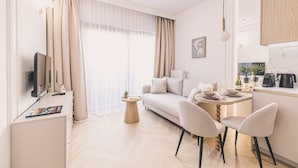 A modern living room with a sofa, two chairs, a small table, and a television. - Estilo Designerski Apartament z Tarasem (gmina Parzęczew)