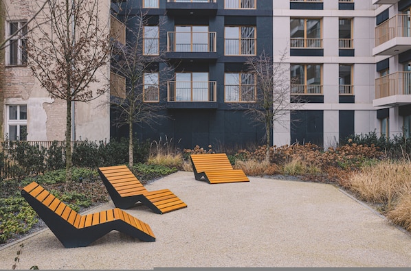 A modern building with multiple balconies, outdoor seating, and a garden area.