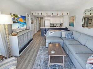 Een moderne woonkamer met een bank, salontafel en een televisie waarop een strand te zien is.