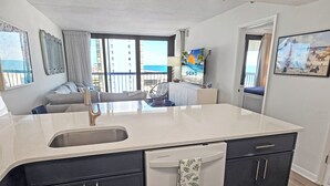 A modern kitchen with a large island, built-in dishwasher, and dark cabinetry. - Direct Oceanfront 3 Bedroom Condo with Outdoor, Indoor, and Kiddie Pools! Sea Watch #909 (Ocean City)