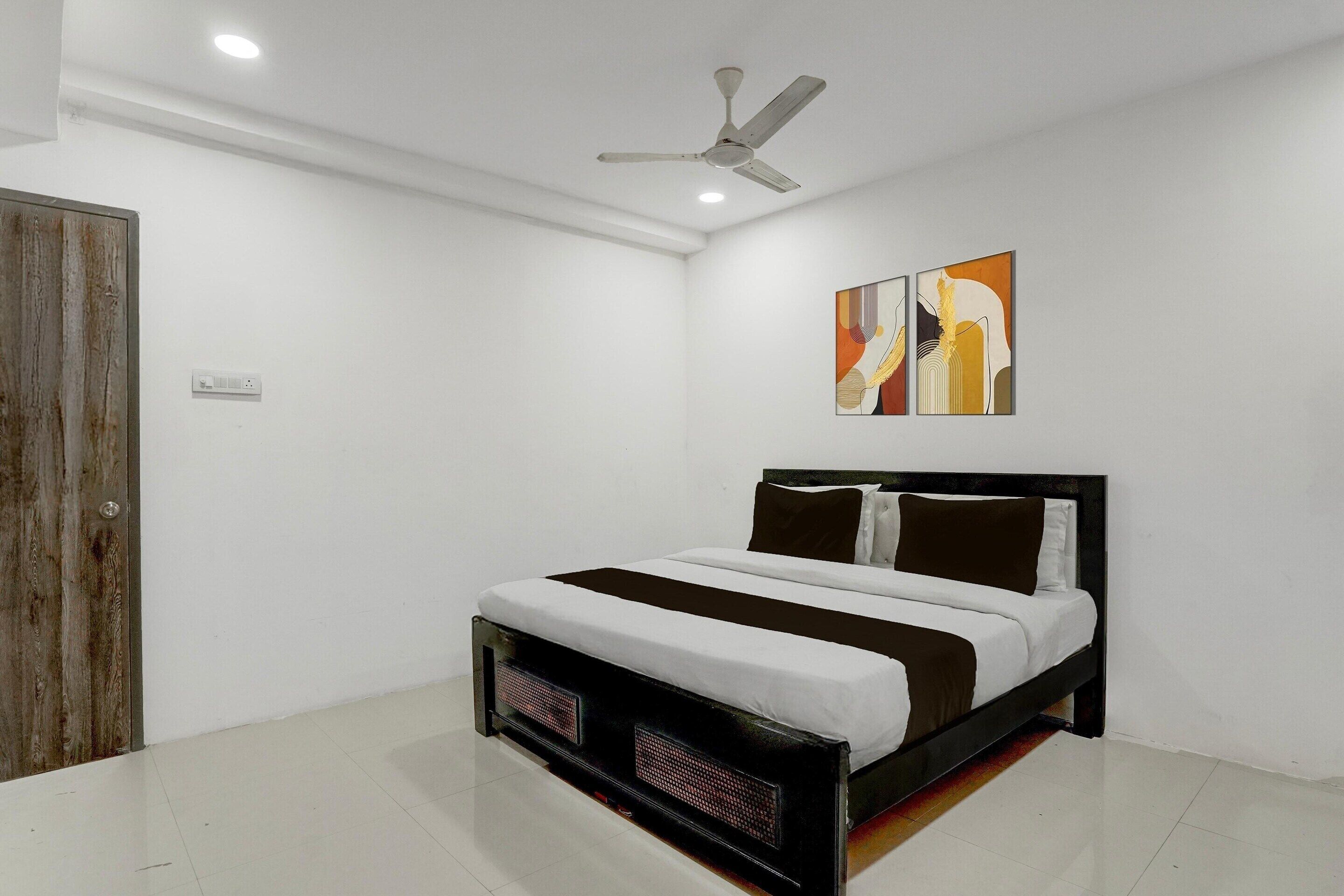 A bedroom with a bed, a ceiling fan, a wall-mounted artwork, and a wooden door.