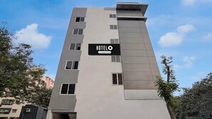 A modern hotel building with a sign reading 'HOTELO' and a company-serviced logo. - Deluxesriman Stay INN (Hyderabad)