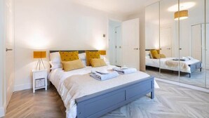 A bedroom with a bed, bedside tables, a mirror, and a wardrobe. - Hame By The Sea, Super Apartment (Largs)