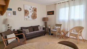 A living room with a sofa, chairs, a coffee table, a lamp, and a painting on the wall. - Plouneour-trez Holiday Home With Seaview (Plounéour-Brignogan-Plages)