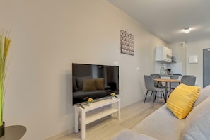 Un salon moderne doté d’un téléviseur à écran plat, d’un canapé, d’une table basse et d’un coin repas avec des chaises et une table.