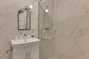 Une salle de bain avec un lavabo blanc, un miroir et une douche.