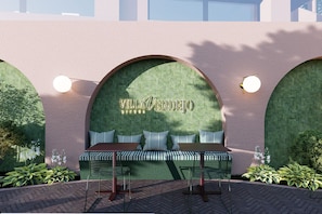 A seating area with a bench and chairs, a wall with a name sign, and two wall-mounted lights. - Villa Verdejo Sitges · Luxury 8-Bedroom, 9-Bathroom Villa with Pool & Spa (Olivella)