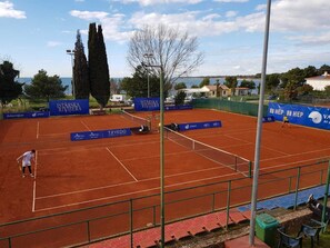Ein Tennisplatz mit Werbung, Netz und einem Spieler.