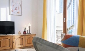 A living room with a TV, wooden cabinet, and a window with yellow curtains. - 3-room apartment in Piazza Brescia, 50m to sea. (Lido di Iesolo)