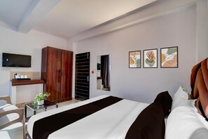 A hotel room with a bed, a TV, a wardrobe, a small table with a plant, and artwork on the wall. - Deluxeaakarshan Residency (New Delhi)