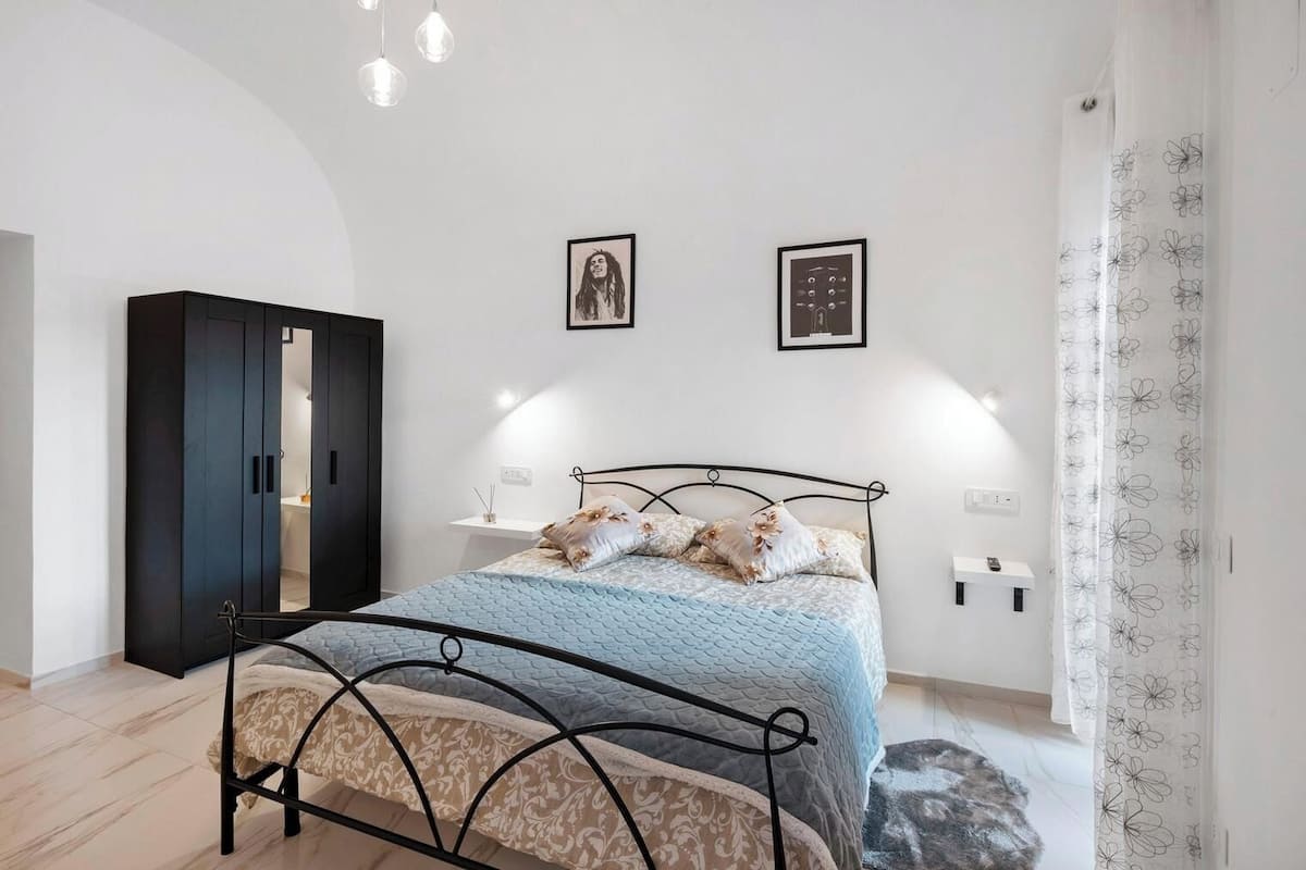 Une chambre à coucher comprenant un lit, une armoire, deux lampes fixées au mur et un rideau.