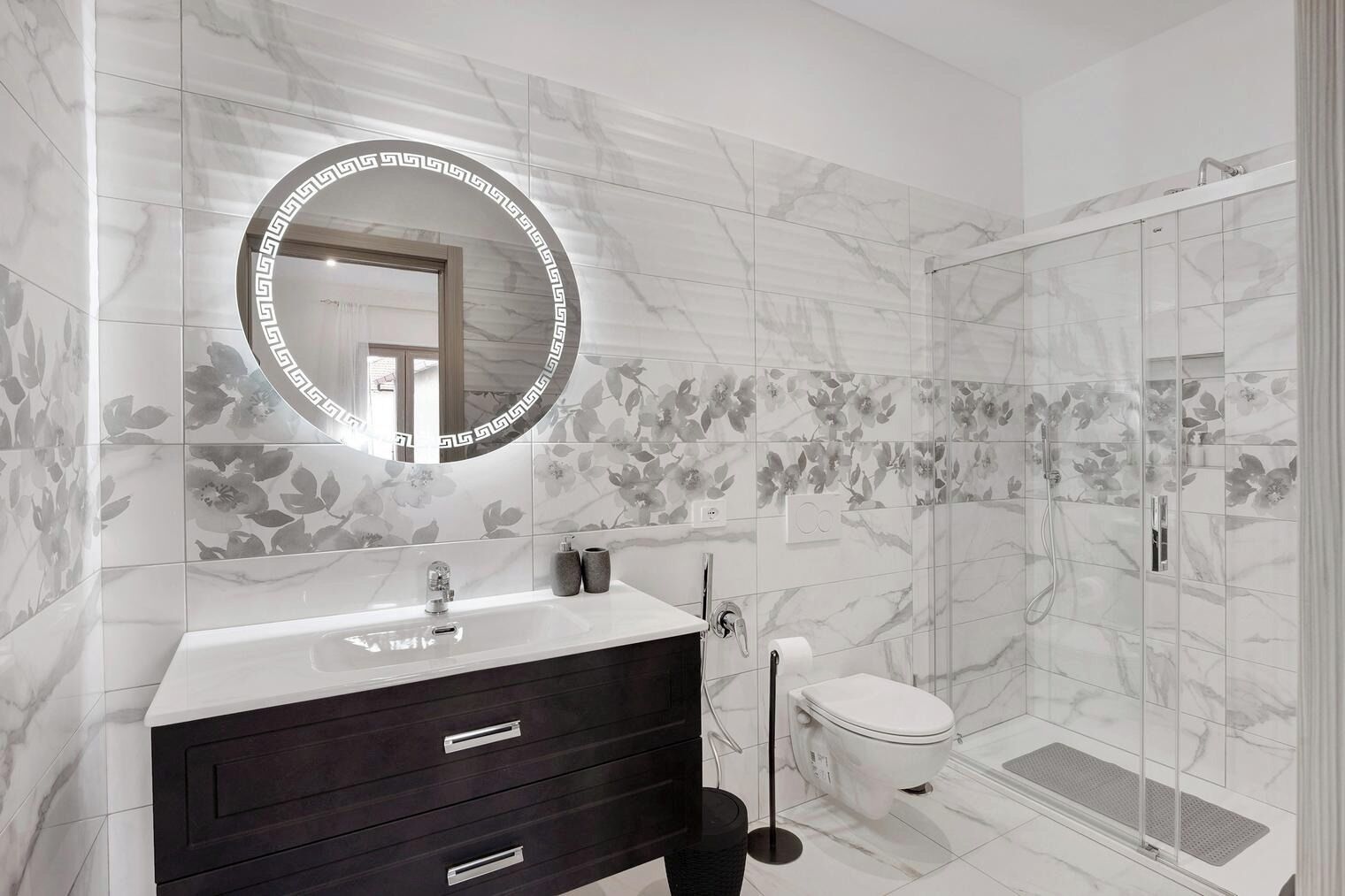 A bathroom with a marble vanity, a toilet, and a shower enclosure.