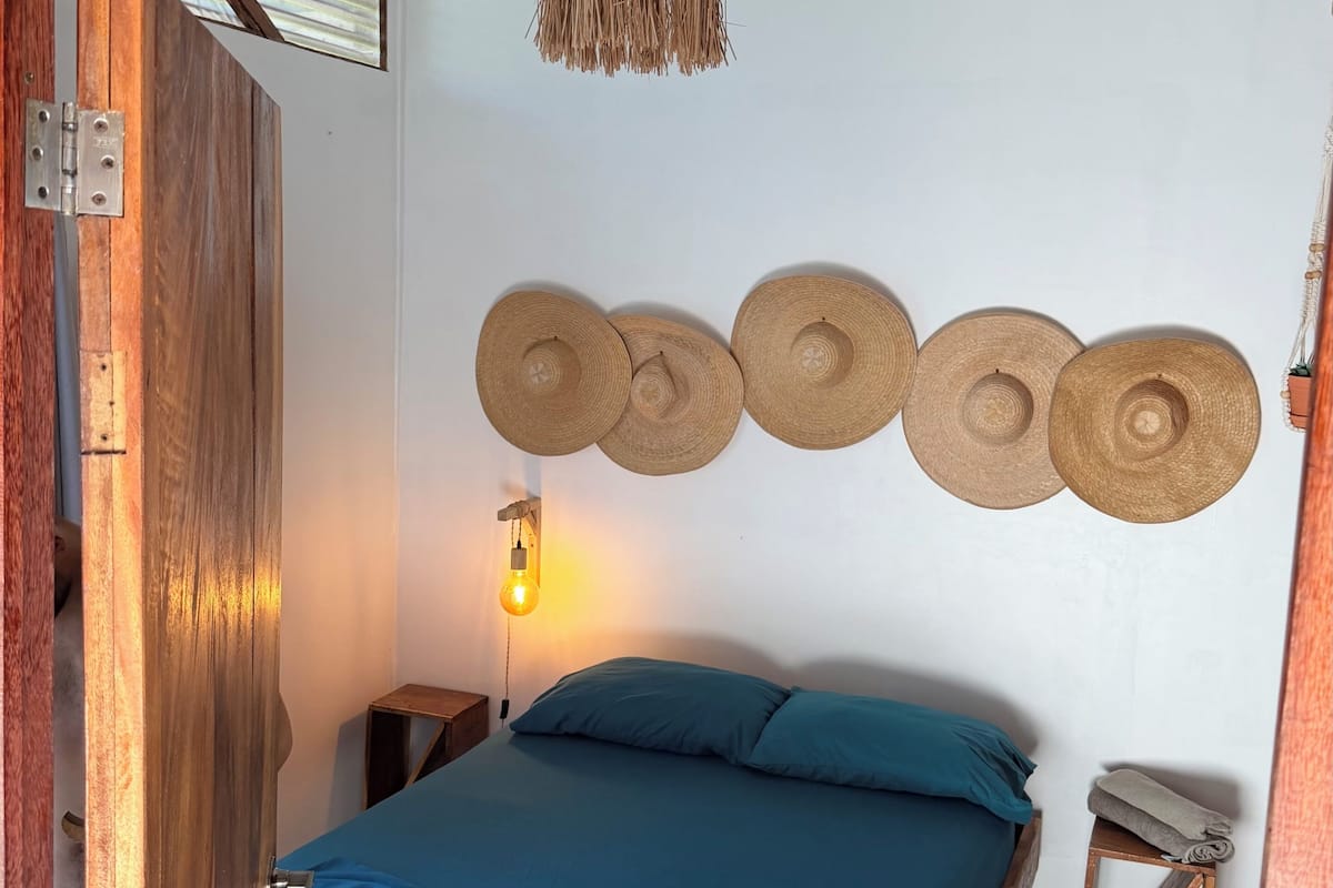 A room with a bed, a wall-mounted light, and a wooden door.