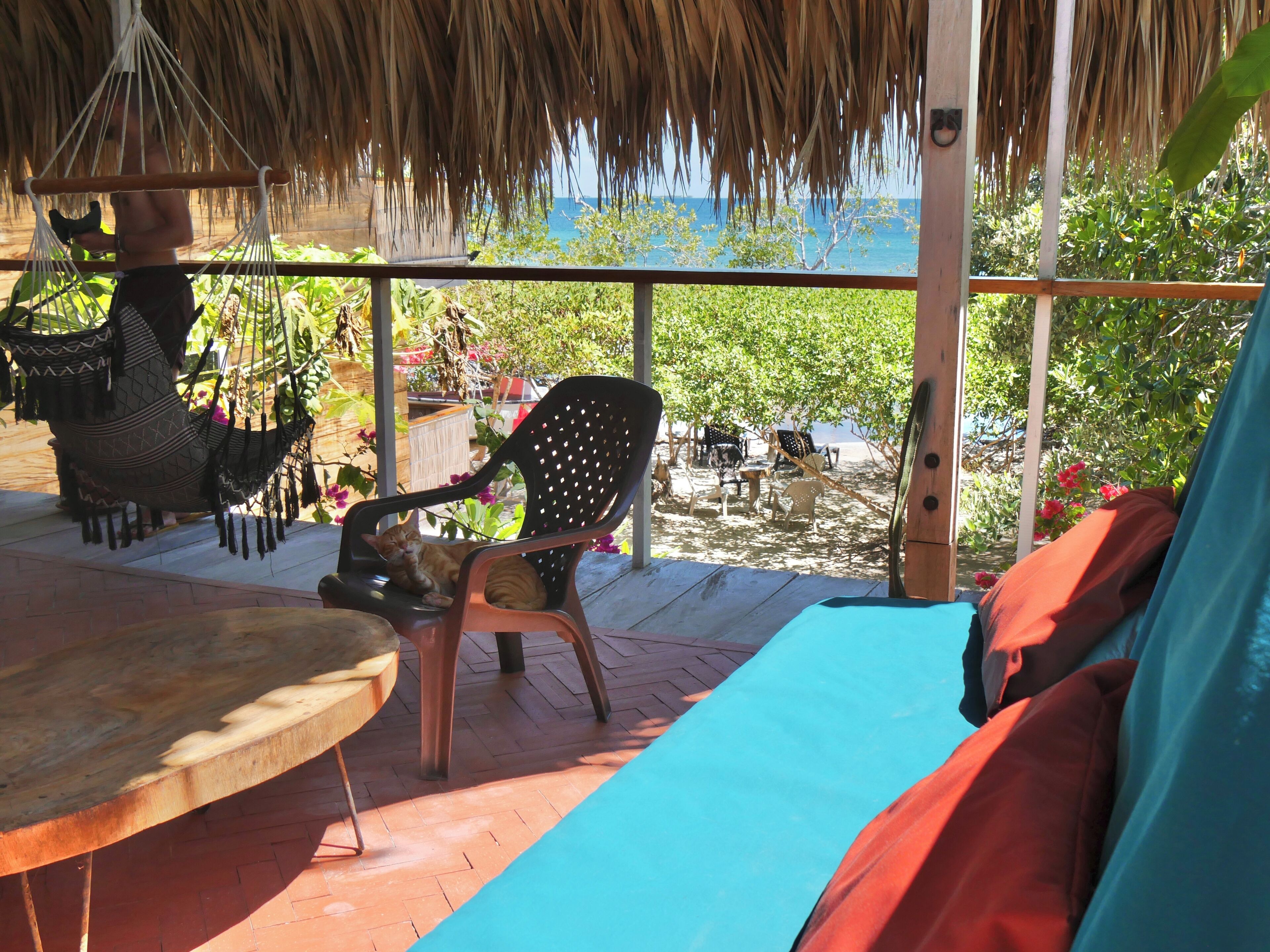 Un espacio de descanso en la playa con una hamaca, una silla y una mesa.