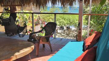 Un espacio de descanso en la playa con una hamaca, una silla y una mesa.