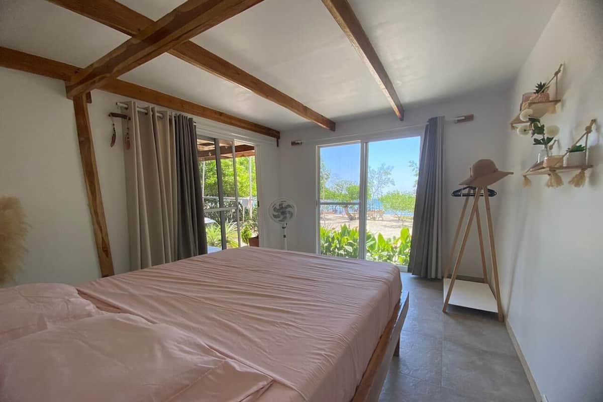 A bedroom with a bed, a fan, and a view of the outdoors.