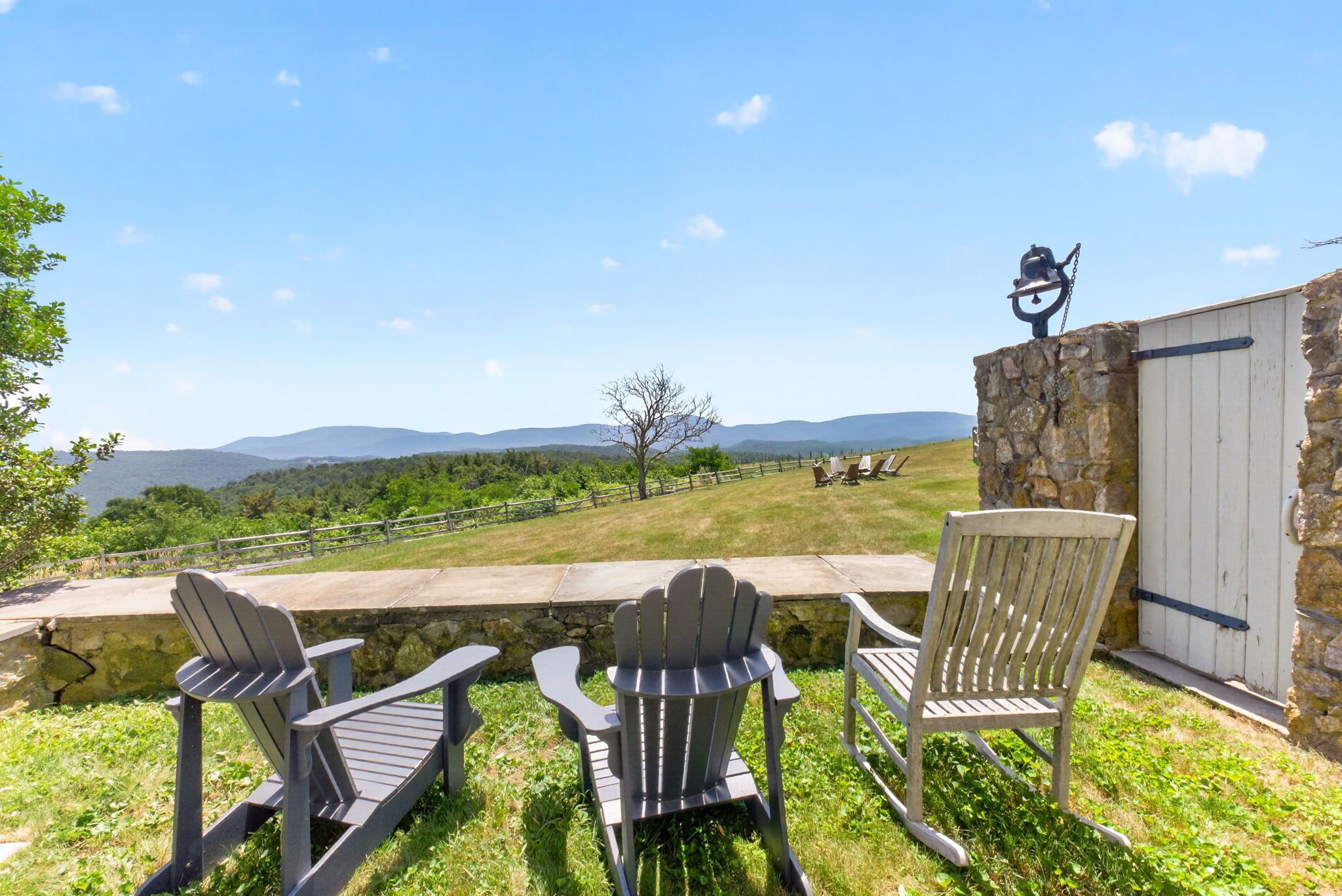 Une terrasse avec des fauteuils Adirondack donnant sur un paysage pittoresque.