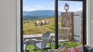 Une pièce dotée d’une porte-fenêtre coulissante donnant sur une terrasse avec coin salon extérieur et vue sur un vignoble.