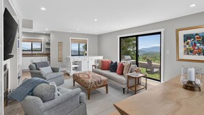 Un salon moderne avec un canapé, des fauteuils, une table basse et une vue sur l’extérieur.