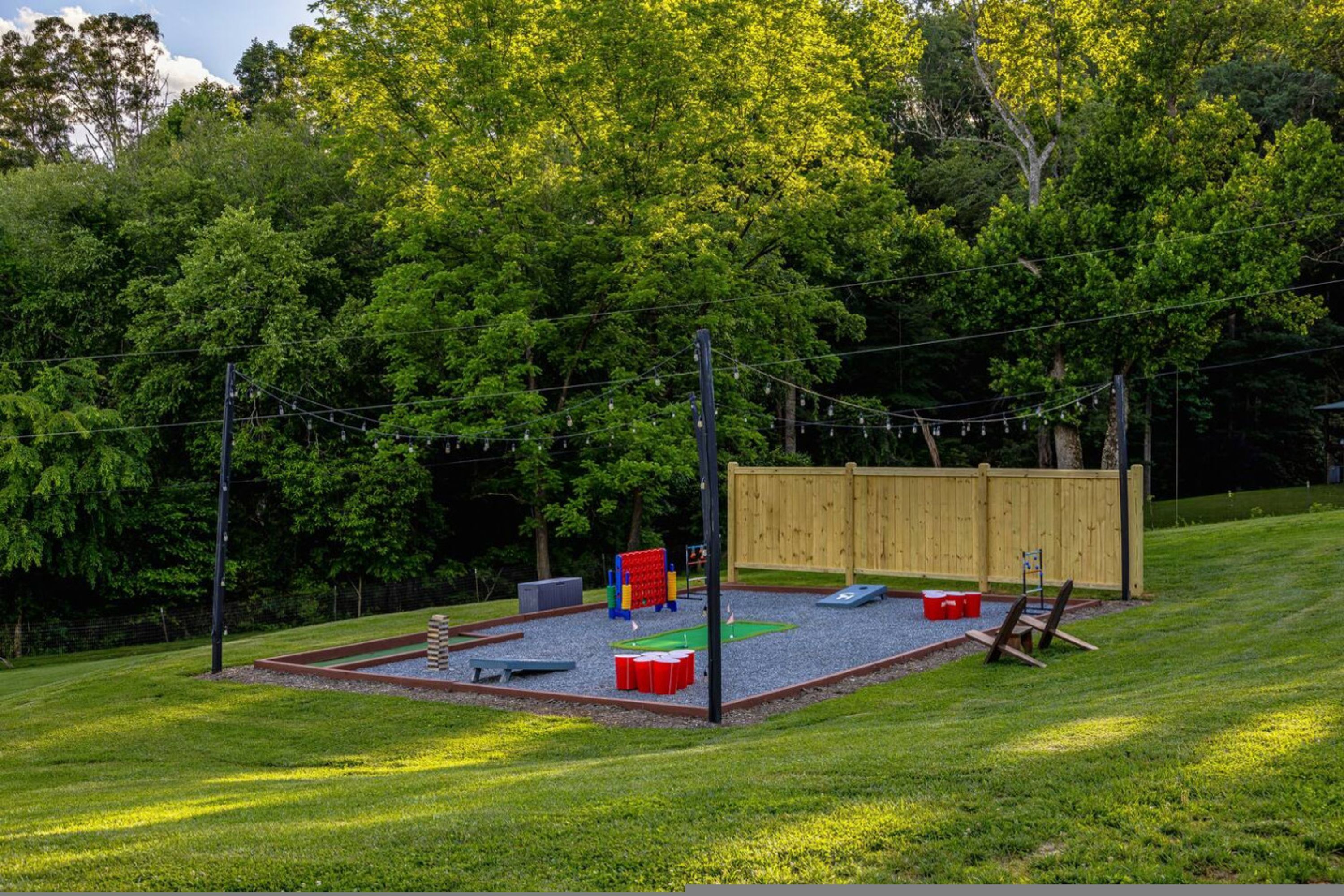 A playground with a wooden fence, play structures, and a gravel area.