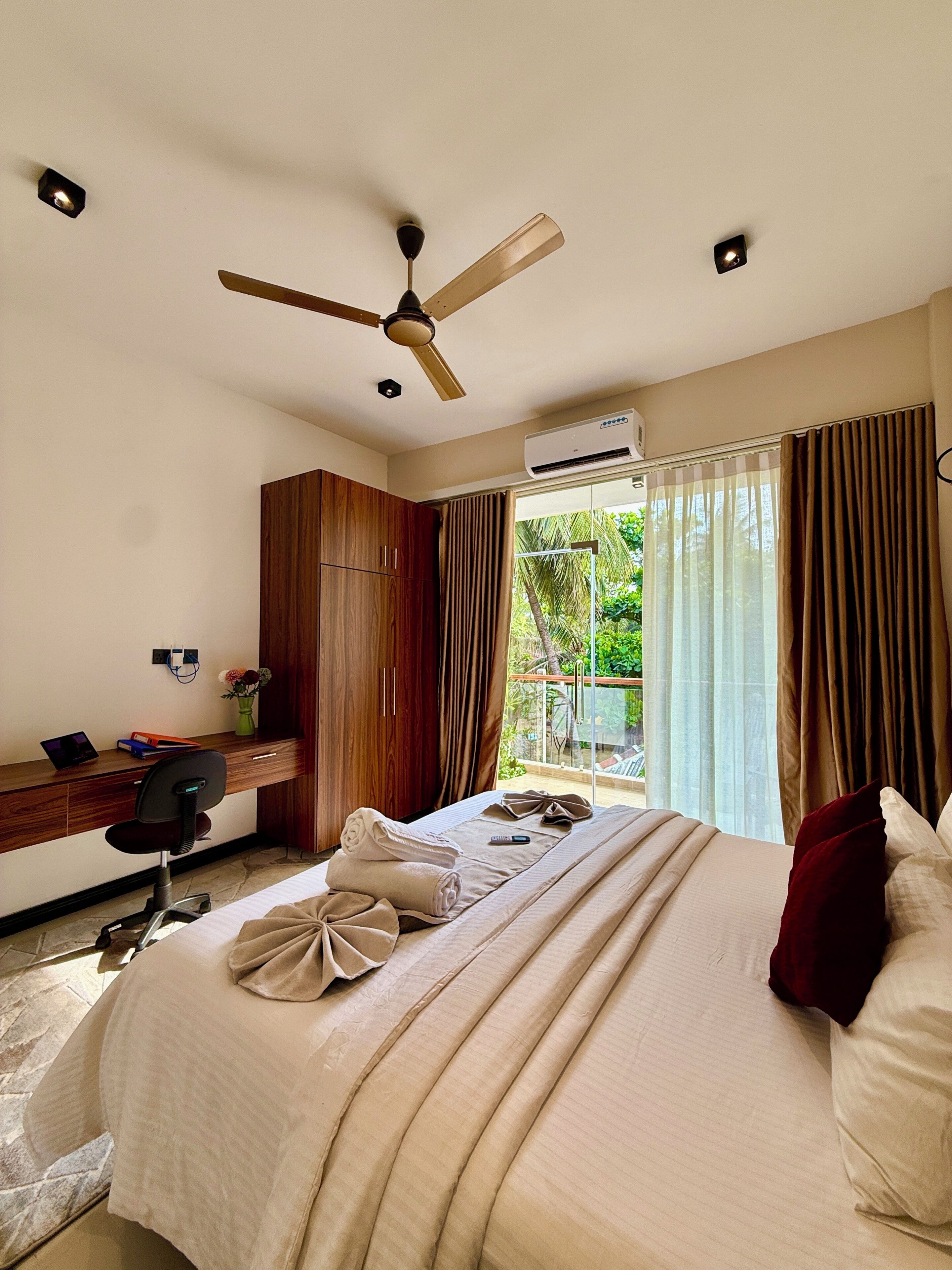 Una habitación de hotel con cama, escritorio, silla y ventilador de techo.