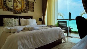 A hotel room with a bed, a large window with curtains, a balcony with a chair, and artwork on the wall.