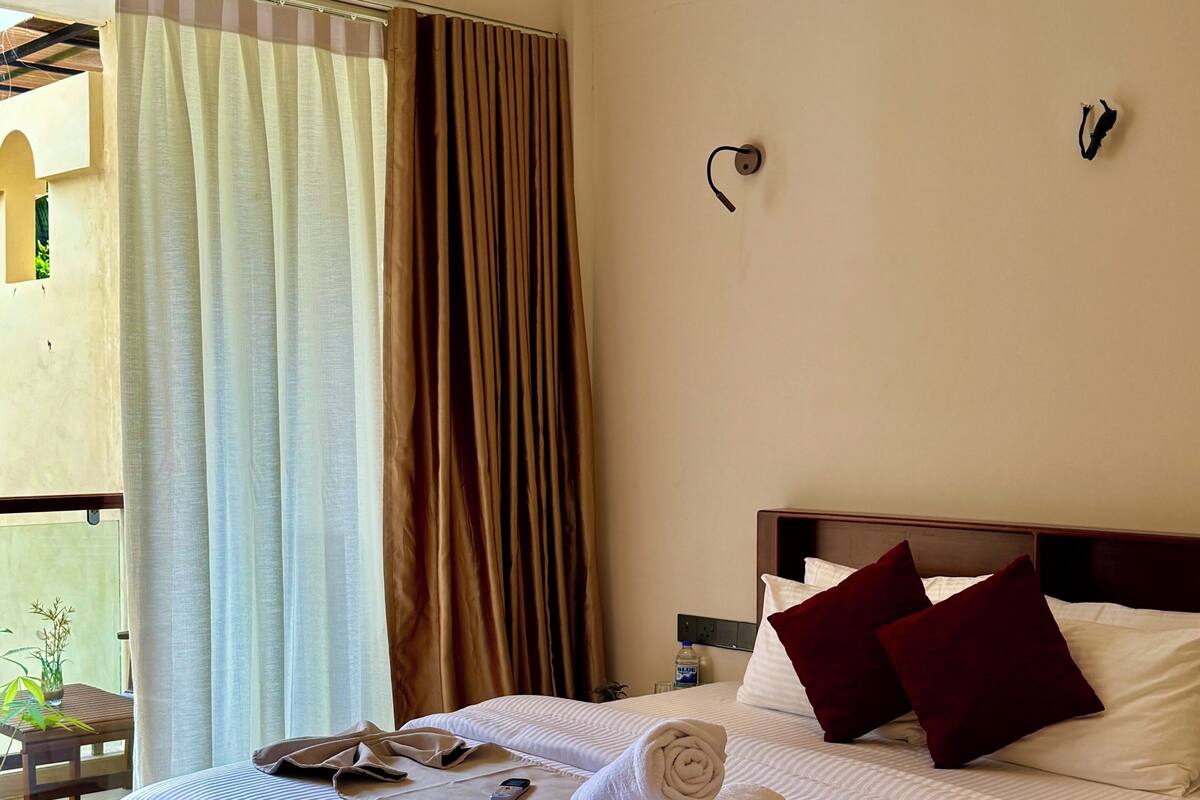 Ein Hotelzimmer mit einem Bett, einem Nachttisch, einem Telefon und einer Wandleuchte.