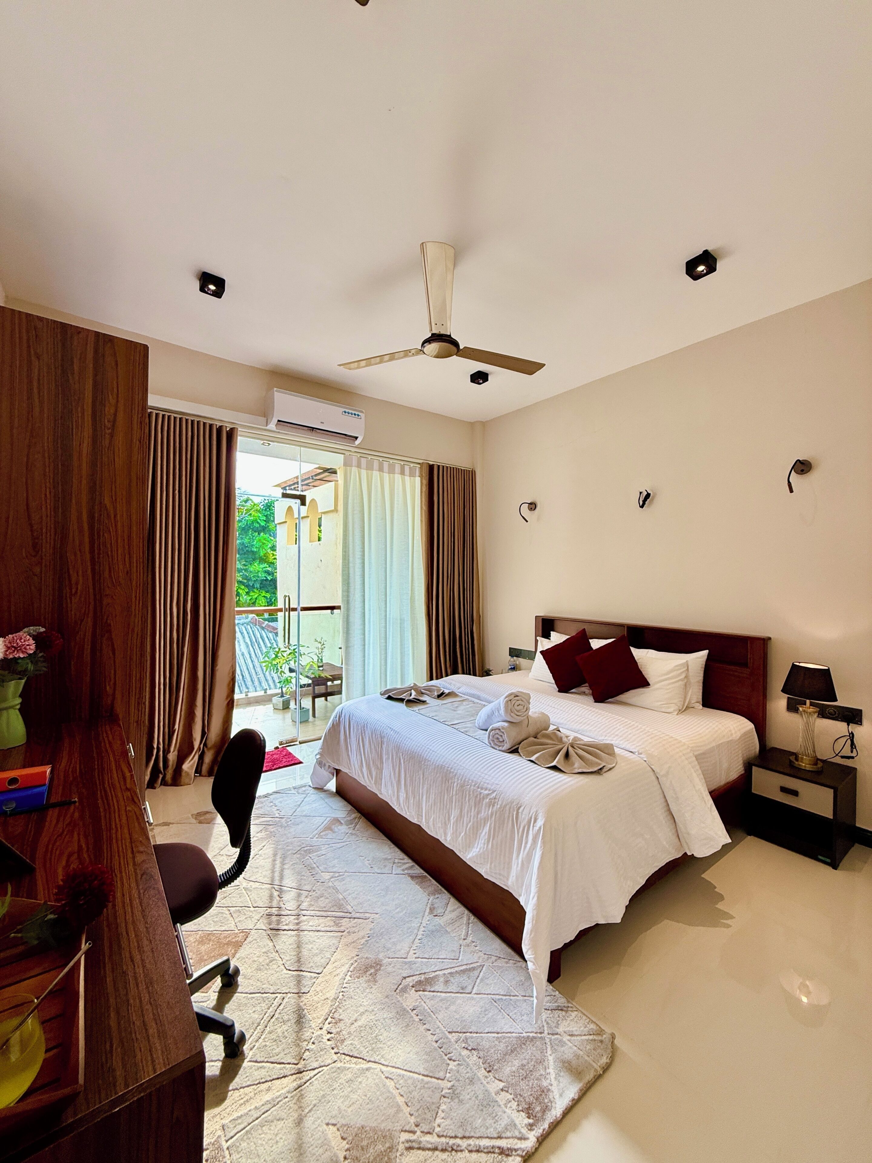 Una habitación de hotel con cama, mesita de noche, escritorio, silla y equipo de aire acondicionado.