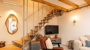 A modern living room with a wooden staircase, a flat-screen TV, a sofa, and a dining area. - Villa Jele (Dubrovnik)