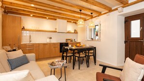 A modern kitchen with wooden beams, a dining area with a table and chairs, and a cozy seating area with a sofa and armchairs. - Villa Jele (Dubrovnik)