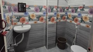 Un baño con ducha, inodoro y lavamanos, con diseños de azulejos florales y un ventanal pequeño.