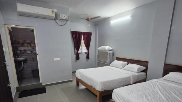 Una habitación con dos camas, ventilador de techo, aire acondicionado y una puerta que da a un baño.