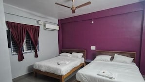 Una habitación con dos camas, ventilador de techo, aire acondicionado y ventana con cortinas.